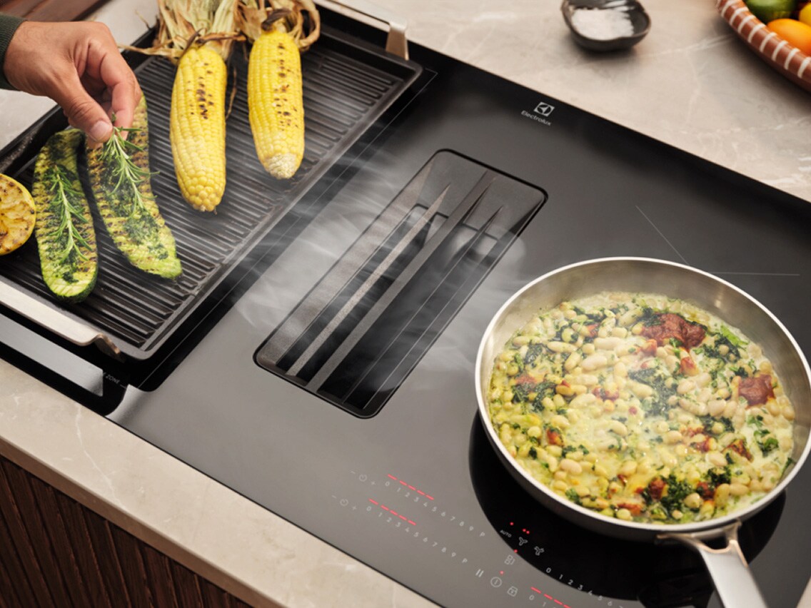 Different types of food are being prepared on an extractor hob.