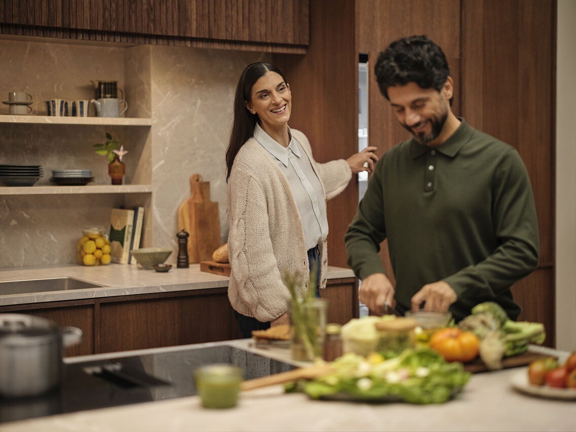 A man and a woman are cooking together in a kitchen.