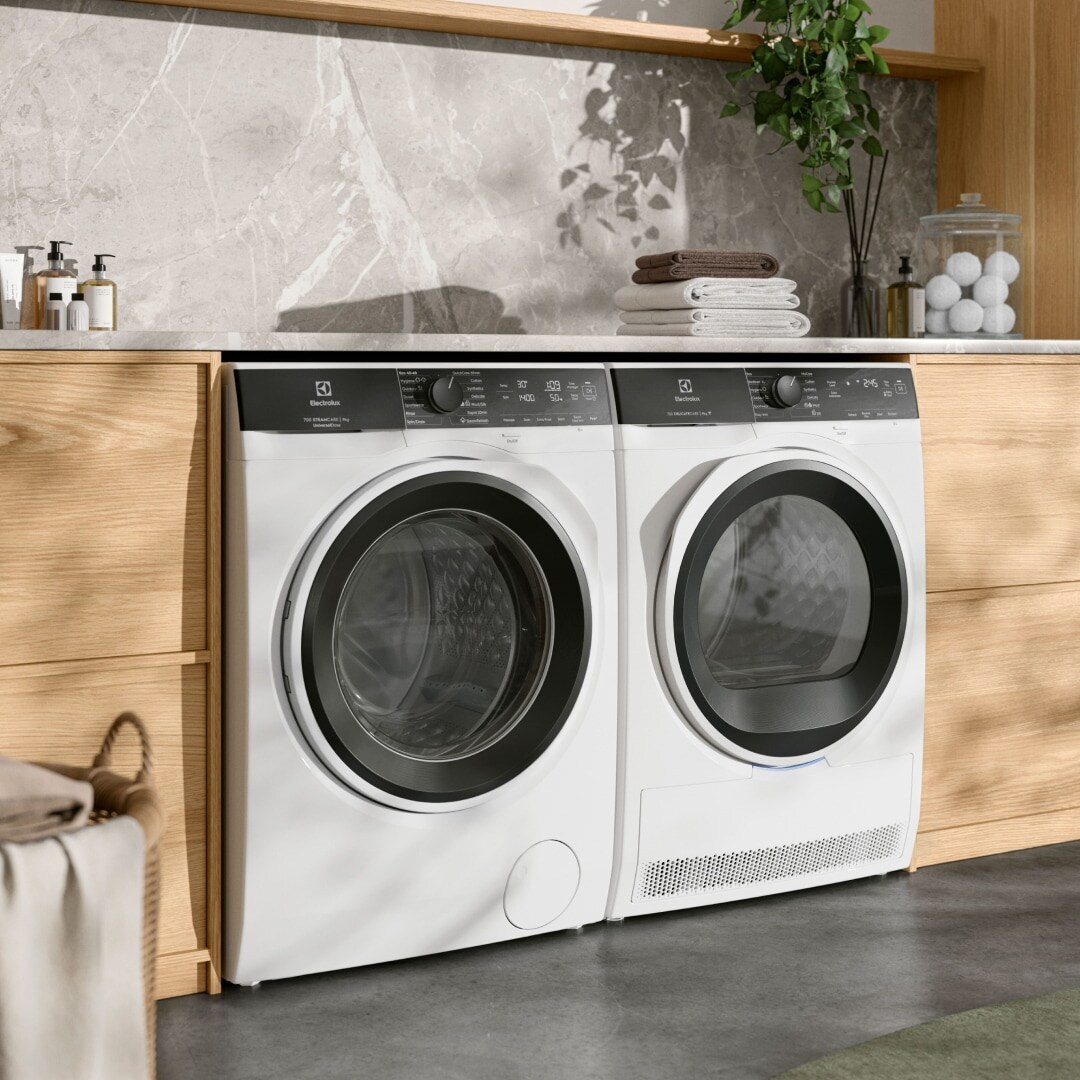 Tumble dryer and washing machine under a bench.